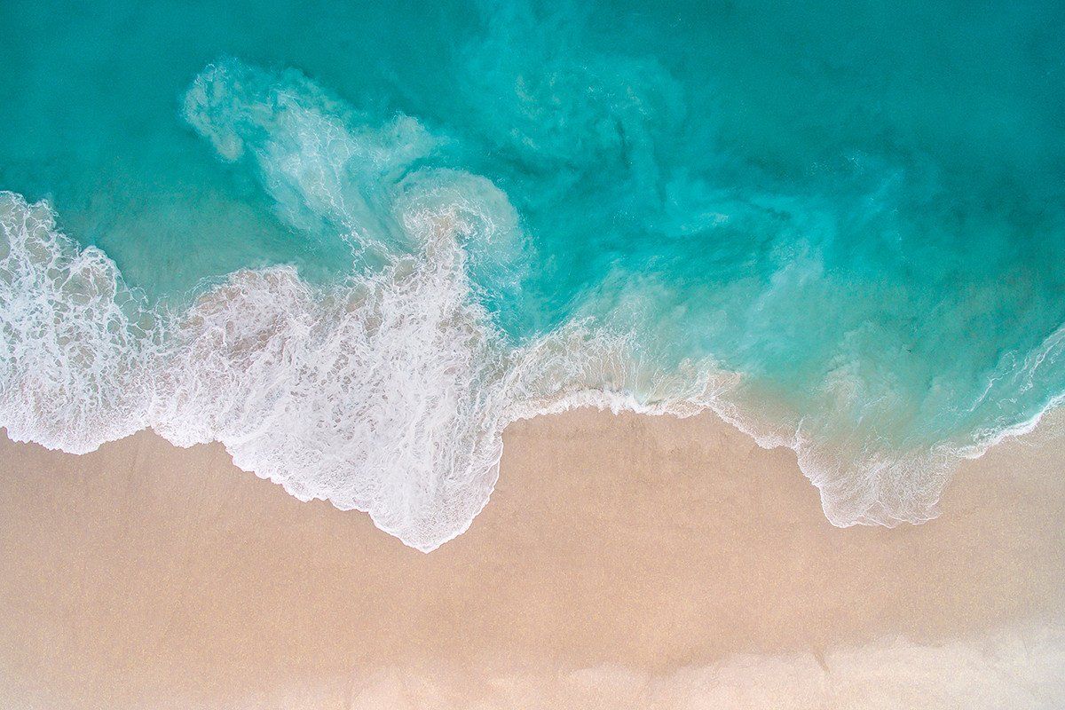 Turquoise water meeting white sand, seen from above